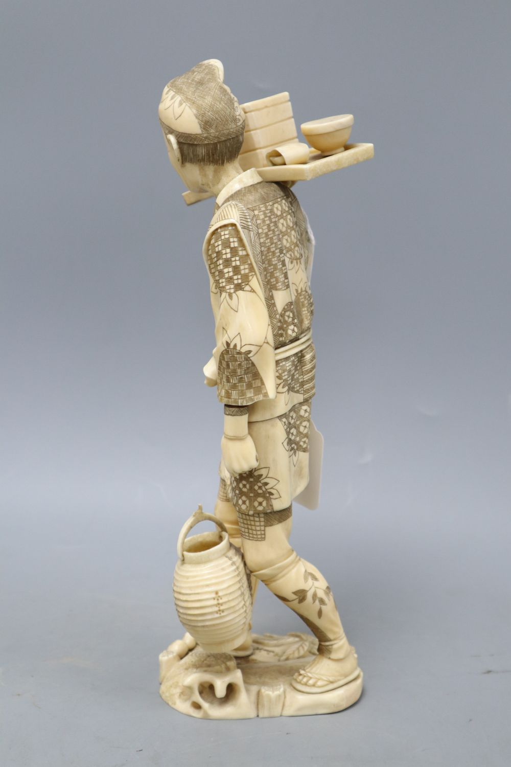 A Japanese Meiji walrus ivory figure of a tradesman, height 32cm